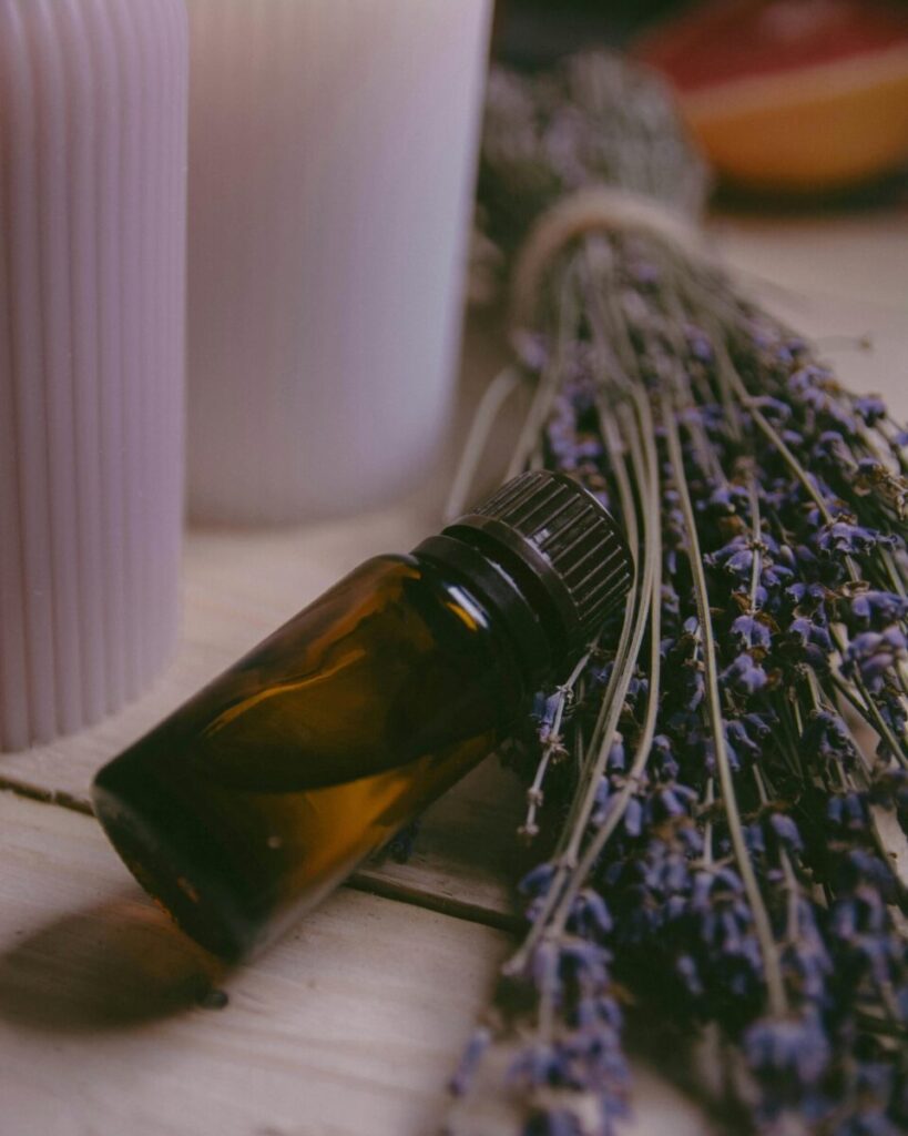 Calming lavender, essential oil bottle, and candles for aromatherapy on a wooden surface.